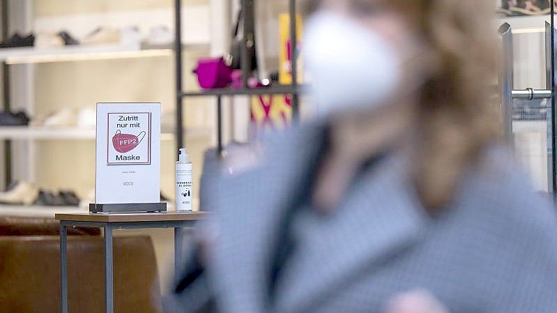 Ein Schild am Eingang eines Schuh-Geschäfts weist auf die Pflicht zum Tragen einer FFP2-Maske hin. Foto: Monika Skolimowska/dpa-Zentralbild/dpa