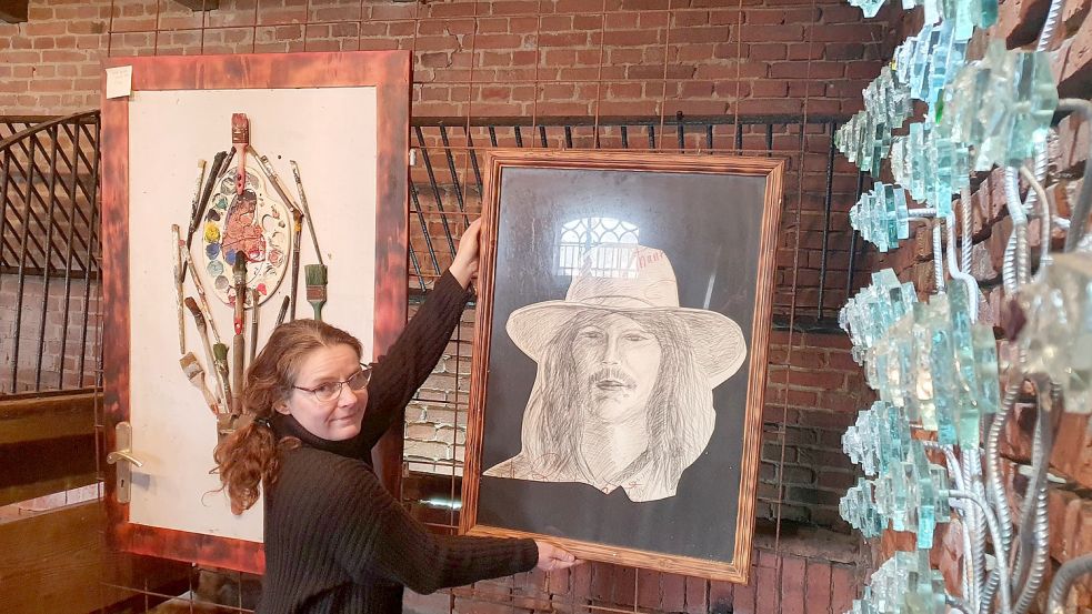 Gemma van Leeuwen hängt ein Selbstporträt von Frans Epping zurecht. Mit einer Retrospektive des niederländischen Künstlers, der seit 2019 eine Galerie in Augustfehn hat, kehrt nach zweijähriger Pause wieder Leben ins Kunstzentrum ein. Foto: Gettkowski