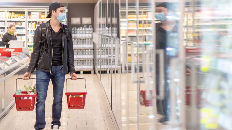 Ein Kunde geht in einem Supermarkt einkaufen und trägt dabei eine Maske. Die staatlich verordnete Maskenpflicht beim Einkaufen fällt in weiten Teilen Deutschlands weg, wenn die Geschäfte am Montag öffnen – gewisse Schutzvorkehrungen könnten aber bleiben. Foto: Michael/dpa-Zentralbild/dpa