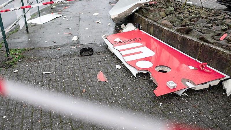 Ein zerstörtes Schild mit dem Logo der Sparkasse liegt auf dem Boden nahe eines gesprengten Geldautomaten. Foto: Fabian Strauch/dpa