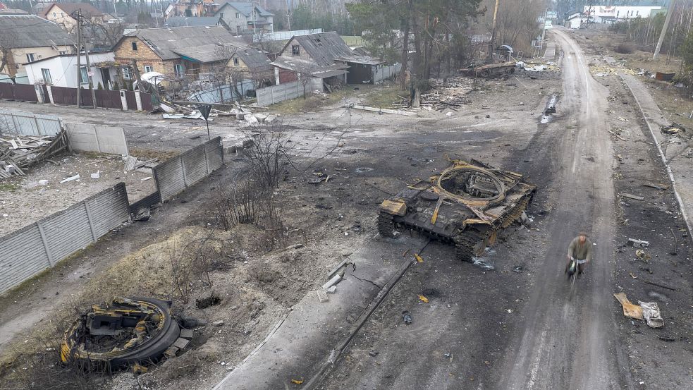 Ein Fahrradfahrer fährt auf einer Straße in einem Vorort von Kiew an einem zerstörten russischen Panzer vorbei. Foto: Rodrigo Abd/AP/dpa