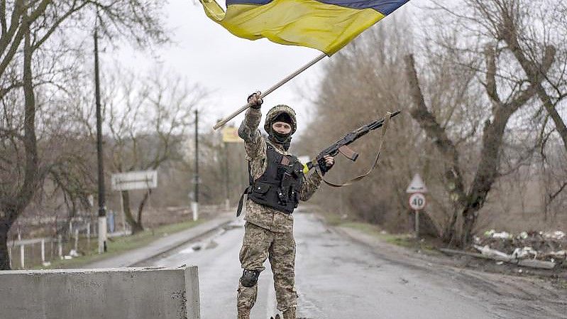 Ein ukrainischer Soldat schwenkt die ukrainische Flagge auf einer Straße in Butscha. Foto: Rodrigo Abd/AP/dpa