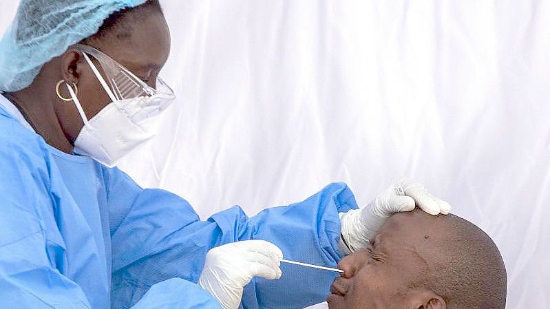 Eine Mitarbeiterin des Gesundheitswesen nimmt zur Bekämpfung der Corona-Pandemie einen Nasen-Abstrich eines Mannes. Foto: Themba Hadebe/AP/dpa