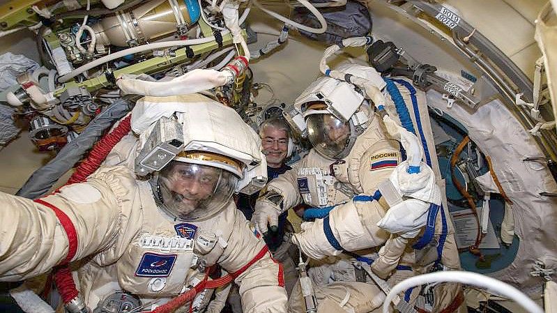 Die russischen Kosmonauten Anton Schkaplerow (l) und Pjotr Dubrow (r) bereiten sich mit Unterstützung von NASA-Astronaut Mark Vande Hei (hinten) auf einen Weltraumspaziergang vor. Foto: Kayla Barron/NASA/dpa