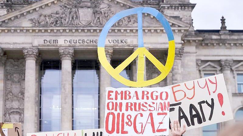 Ein Peace-Zeichen in den ukrainischen Farben und Protestplakate vor dem Reichstagsgebäude. Foto: Annette Riedl/dpa