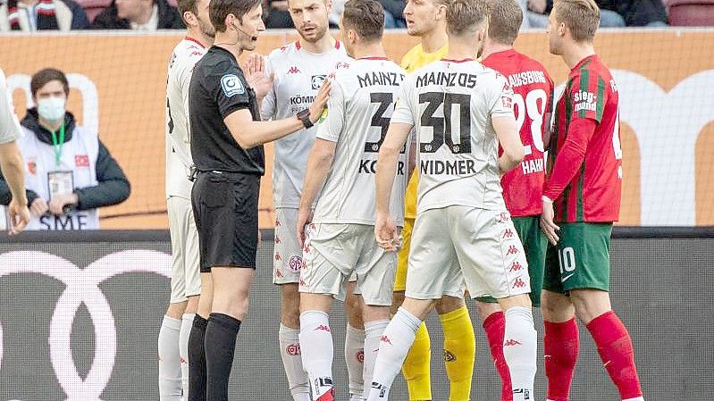 Die Mainzer Spieler diskutieren mit Schiedsrichter Matthias Jöllenbeck (l). Foto: Matthias Balk/dpa