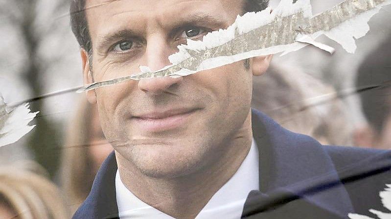 Ein zerrissenes Plakat des französischen Präsidenten Emmanuel Macron für die Präsidentschaftswahl klebt in Paris. Foto: Francois Mori/AP/dpa