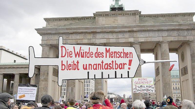 Impfpflicht-Gegner stehen bei einer Kundgebung vor dem Brandenburger Tor in Berlin, während der Bundestag über die Einführung einer Impfpflicht debattiert. Foto: Paul Zinken/dpa