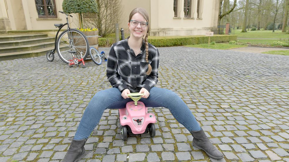 Volontärin Dorothee Hoppe auf einem pinken Bobbycar. Im Hintergrund stehen noch weitere Fahrzeuge zum Ausprobieren bereit: ein Hochrad, ein Artistenrad und ein Einrad. Foto: Ortgies