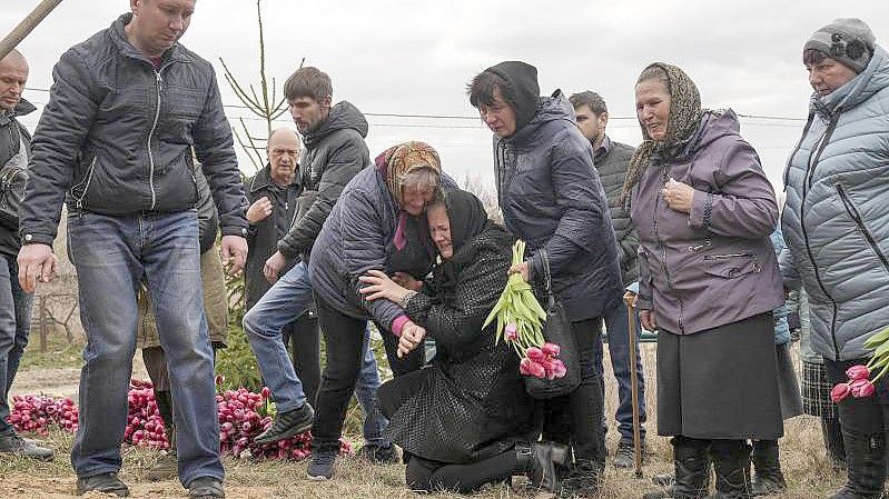 Liudmila Sumanschuk (m.) während der Beerdigungszeremonie in Tschernihiw für ihr Enkelkind Veronika Kuts. Die 12-Jährige kam bei einem Bombardement ums Leben. Foto: Evgeniy Maloletka/AP/dpa