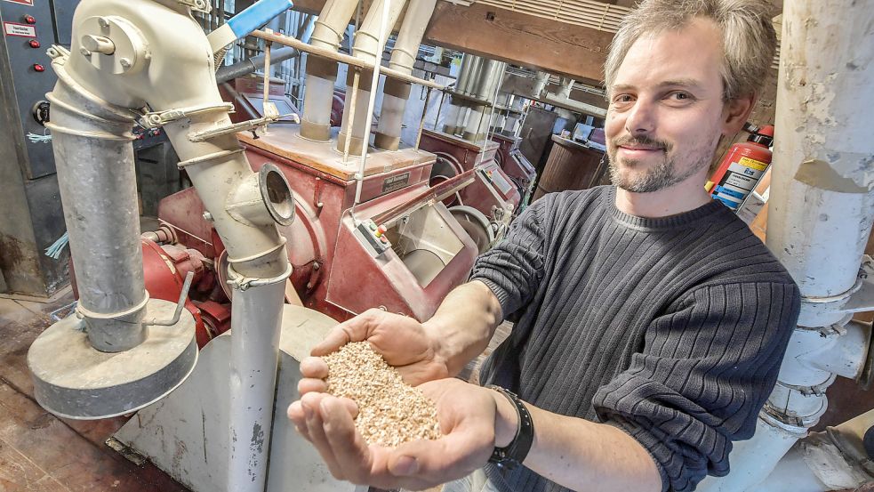 Da ist noch viel Zerkleinerungsarbeit erforderlich: Heiko Vosberg hält Schrot in die Kamera. Das Produkt stammt von dem Walzenstuhl im Hintergrund. Fotos: Ortgies