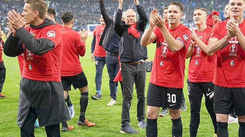 Die Spieler des SC Freiburg freuen sich mit Trainer Christian Streich (M) über den Einzug ins Finale des DFB-Pokals. Foto: Marcus Brandt/dpa