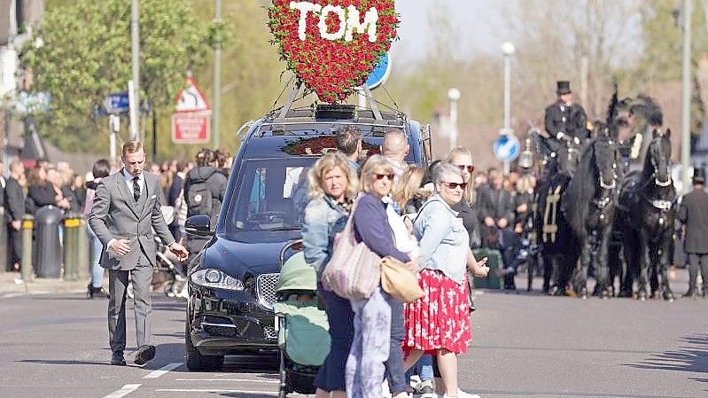 Ein Herz aus Rosen mit der Aufschrift „Tom“ schmückt den Leichenwagen: Viele Menschen nahmen Abschied vom britischen Sänger Tom Parker. Foto: Kirsty O'connor/PA Wire/dpa
