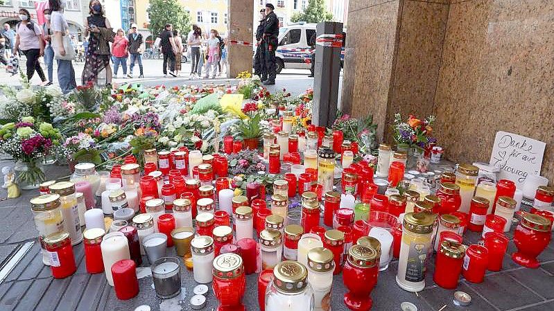 Blumen und Kerzen vor dem abgesperrten Kaufhaus in der Würzburger Innenstadt für die Opfer nach einer Messerattacke. Foto: Karl-Josef Hildenbrand/dpa
