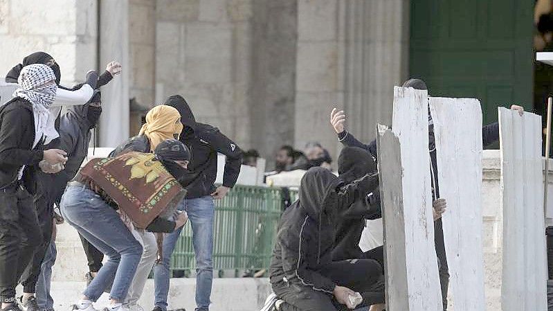Palästinensische Demonstranten benutzen behelfsmäßige Schutzschilde bei Zusammenstößen mit der israelischen Polizei auf dem Gelände der Al-Aksa-Moschee in der Altstadt von Jerusalem. Foto: Mahmoud Illean/AP/dpa