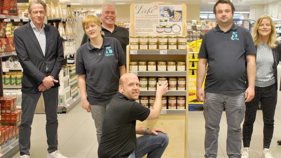 Edeka-Marktleiter André Simmerimg räumt die ersten Gläser Chutney ins Regal. Mit ihm freuen sich Wilhelm Behrends (links), Marie Ubben (rechts) und Mitarbeiter der Fehnwerkstatt Wiesmoor. Foto: Schönig