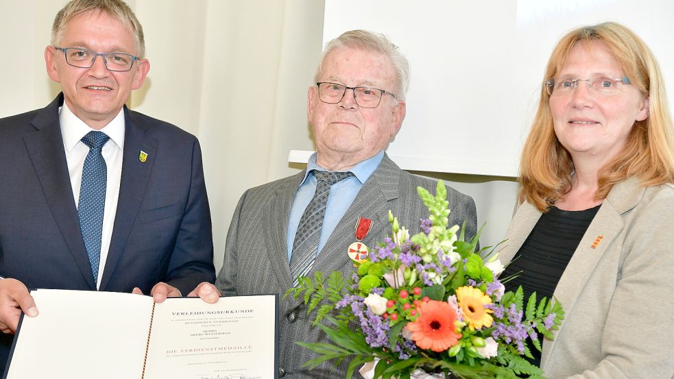 Olaf Meinen (links) überreichte die Verdienstmedaille und die Urkunde an Heere Westerman. Rechts steht Hilke Looden (parteilos), die Bürgermeisterin der Gemeinde Krummhörn. Fotos: Wagenaar