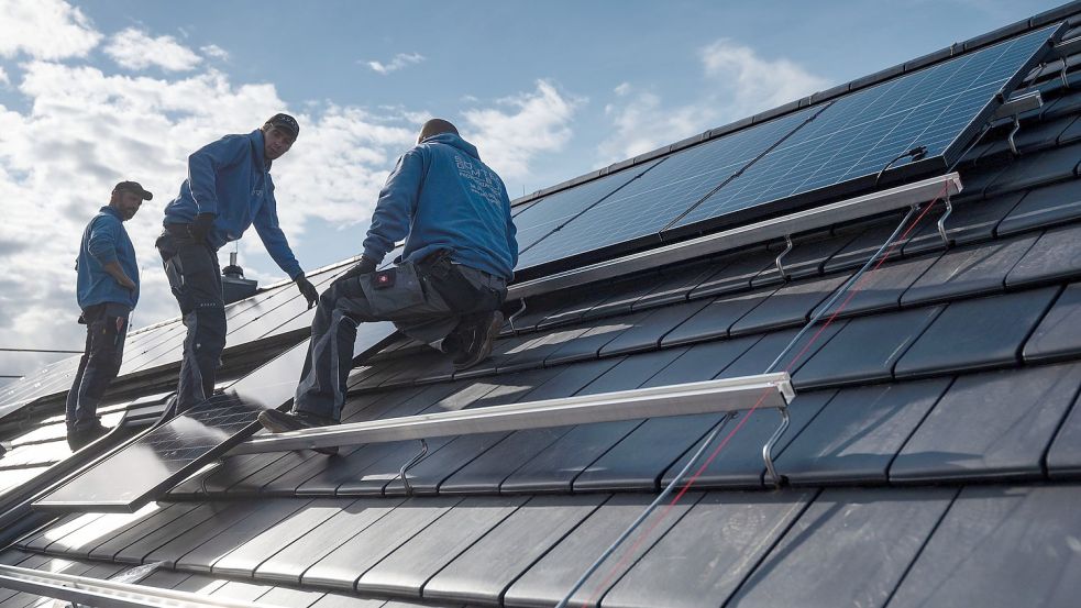 Mitarbeiter der Firma Sontec GmbH montieren Photovoltaikmodule auf dem Dach eines Wohnhauses. Beim Ausbau solcher Anlagen auf städtischen Gebäuden hinkt Emden zurück. Foto: Marijan Murat/DPA