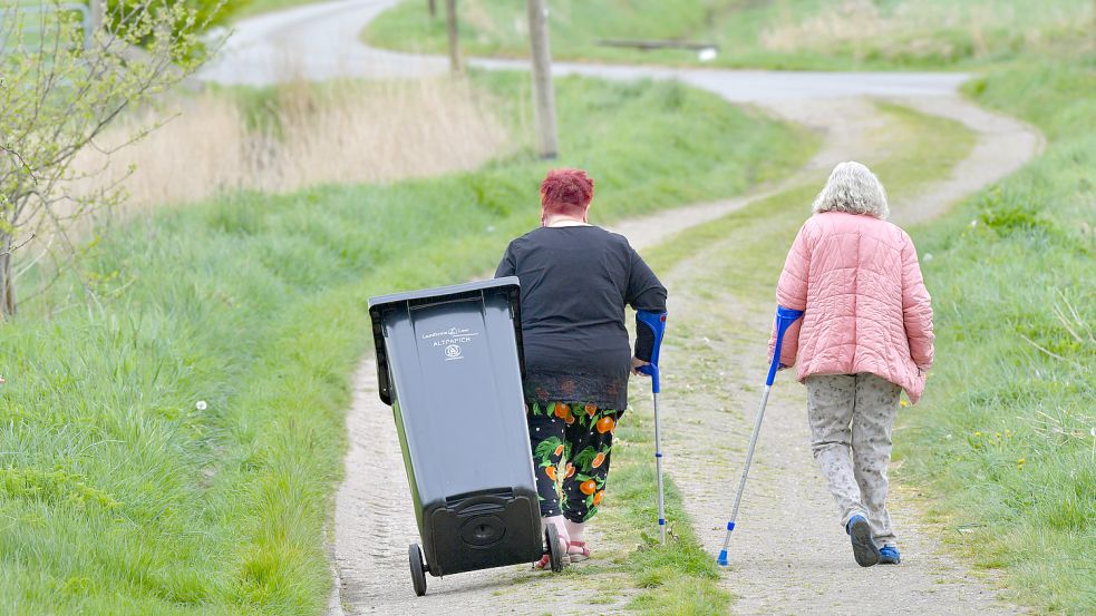 Kerstin Bonepart (links) und Heidi Tippmann bringen die Altpapiertonne zu Fuß zur Kreisstraße 37 in Böhmerwold. Bis zur Abholstelle sind es von ihrem Haus aus rund 1,7 Kilometer. Foto: Ortgies
