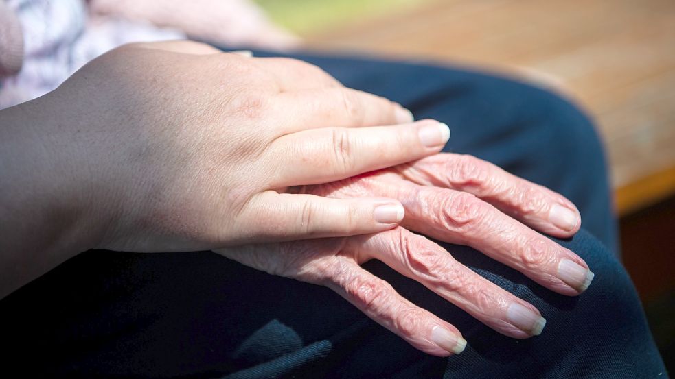 Eine junge Frau berührt die Hand einer Seniorin. Foto: Schuldt/Picture Alliance/DPA