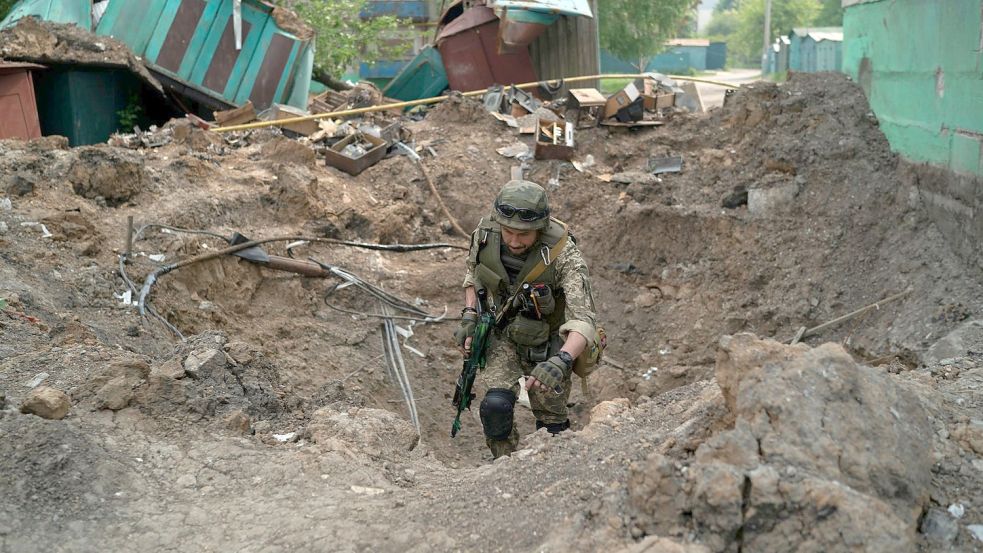 Ein Uniformierter inspiziert einen Krater nach einem Luftangriff der russischen Streitkräfte in der Region Luhansk. Foto: Leo Correa/AP/dpa