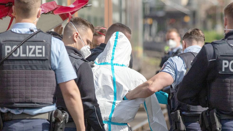Polizisten führen den mutmaßlichen Täter ab. Der Mann soll in einer Regionalbahn mit einem Messer auf Reisende eingestochen haben. Foto: Ralf Roeger/dpa