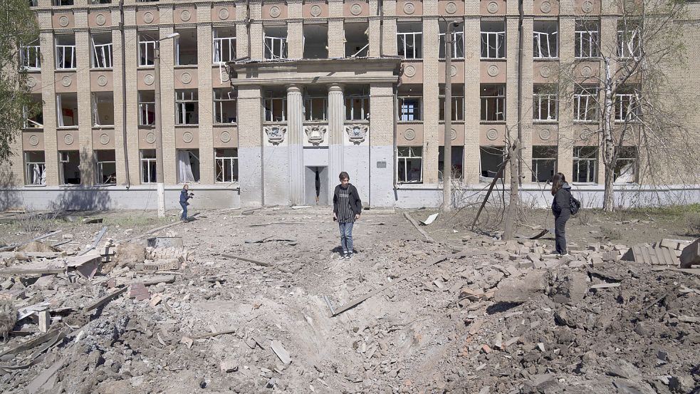 Eine Frau betrachtet den Krater einer Explosion nach einem russischen Luftangriff in Bachmut in der Oblast Donezk in der Ostukraine. Foto: Evgeniy Maloletka/AP/DPA
