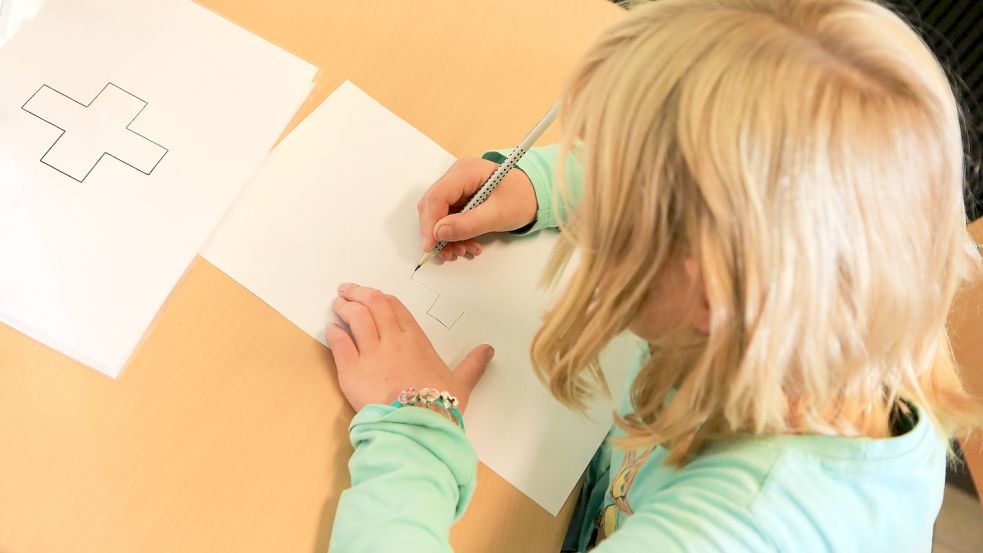Ein Kind malt im Rahmen einer Schuleingangsuntersuchung ein Kreuz auf. Die Mädchen und Jungen werden vielseitig darauf geprüft, ob sie bereit für die Schule sind. Symbolbild: Marcel Kusch/dpa