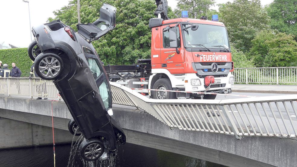 Ein Kranwagen der Feuerwehr zieht den Unfallwagen aus dem Wasser. Foto: F. Doden