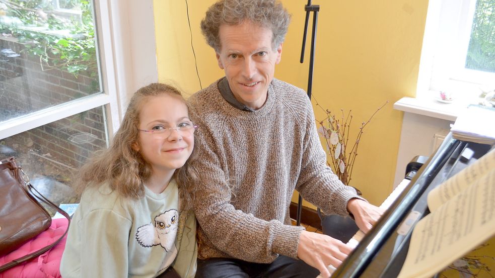 Yara und ihr Vater Iwan König sitzen zusammen am Flügel in ihrem Wohnzimmer. Foto: Hoppe