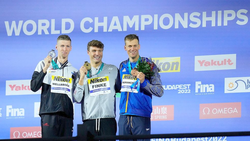 Der Zweitplatzierte Florian Wellbrock (l-r), Sieger Bobby Finke aus den USA, und der Ukrainer Michailo Romantschuk auf dem Podium. Foto: Petr David Josek/AP/dpa