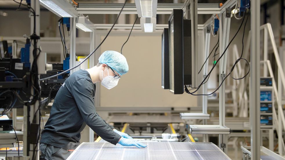 Ein Mitarbeiter prüft ein Solarmodul in einem Werk in Freiberg, Sachsen. Die Nachfrage nach der Technik ist groß, die Lieferschwierigkeiten aber auch. Foto: Sebastian Kahnert/dpa