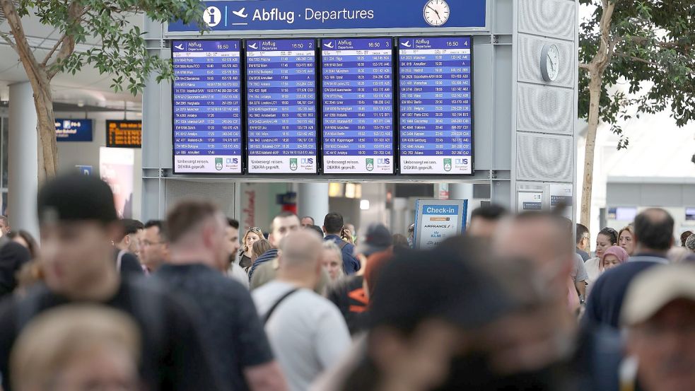 Reisende gehen durch den Flughafen Düsseldorf. Der Ferienstart im bevölkerungsreichsten Bundesland Nordrhein-Westfalen dürfte am Wochenende zu stundenlangen Wartezeiten führen. Foto: David Young/dpa