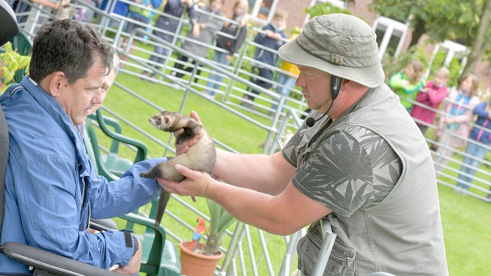 Hier zeigt Tiertrainer Martin Tränkler (rechts) den Bewohnern der Einrichtung Open Dören, Rüdiger Lehmhuis (von links) und Uwe Fokken, ein Frettchen. Foto: Ortgies