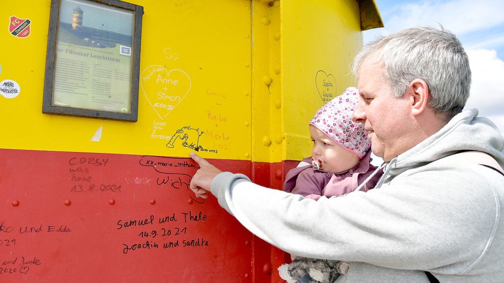 Nicht nur die kleine Laura und ihr Papa Martin aus Essen wundern sich über die Kritzeleien am Pilsumer Leuchtturm. Foto: Wagenaar