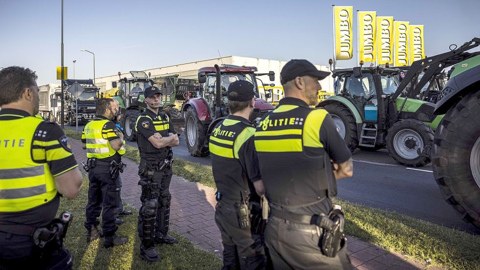 Polizisten stehen neben Traktoren bei einer Protestaktion. Foto: Engelaar/dpa