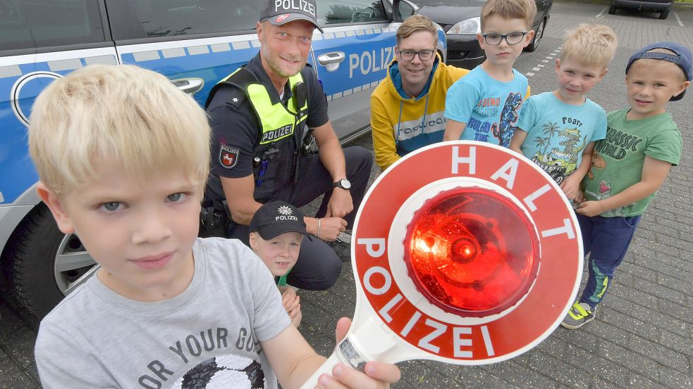 Für ein Verkehrssicherheitstraining war Holger Schulte im Filsumer Kindergarten. Der Polizist wurde unter anderem von Kita-Mitarbeiter Philip Grüssing begleitet. Stolz hält hier ein Junge eine Kelle in der Hand. Foto: Ortgies