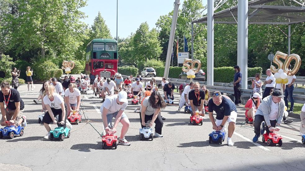 Im Europa-Park ziehen 50 Menschen auf Bobby-Cars den Bus der Kelly Family 50 Meter weit. Foto: Uli Deck/dpa Foto: Uli Deck
