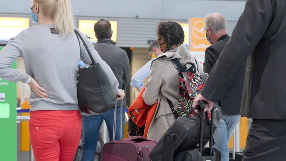 Flugreisende warten in der Abflughalle Terminal 1 des Frankfurter Flughafens vor einem Check-in-Schalter. Foto: Dedert/dpa
