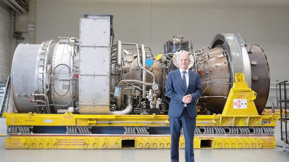 Bundeskanzler Olaf Scholz (SPD) steht vor der in Kanada für die Erdgas-Pipeline Nordstream 1 gewarteten Turbine. Sie steht für den Weitertransport nach Russland bereit. Foto: Bernd Thissen/dpa
