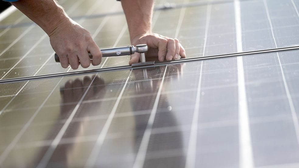 Ein Arbeiter montiert Photovoltaikmodule auf dem Dach eines Wohnhauses. Foto: Marijan Murat/dpa