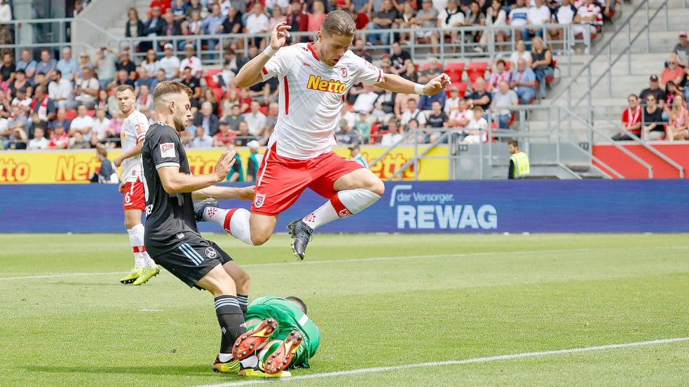 Regensburgs Torhüter Dejan Stojanovic (M) rettet den Ball vor dem Nürnberger Manuel Wintzheimer (l) - Jahn-Spieler Jan Elvedi springt drüber. Foto: Daniel Löb/dpa