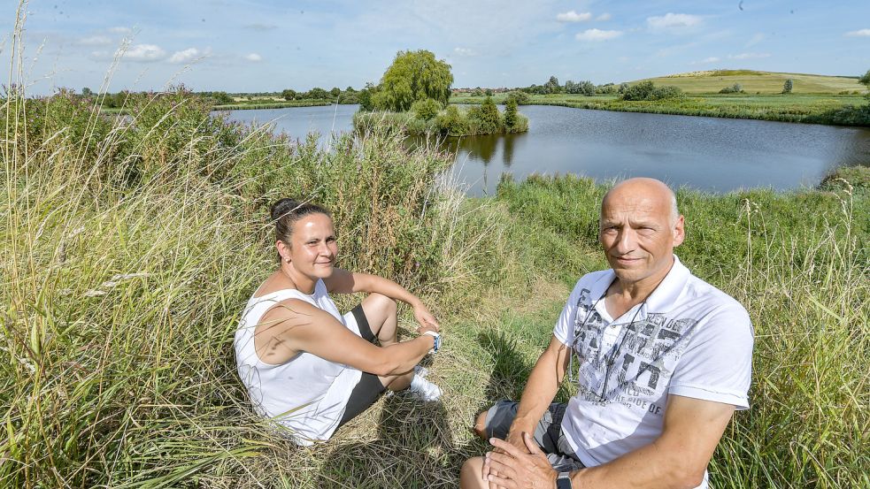 Melanie Veltjes und Wolfgang Wauer sitzen auf dem alten Constantia-Deich an der Einmündung der Grooten Gracht in das Larrelter Tief. Im Hintergrund liegt der Friesenhügel. Foto: Ortgies