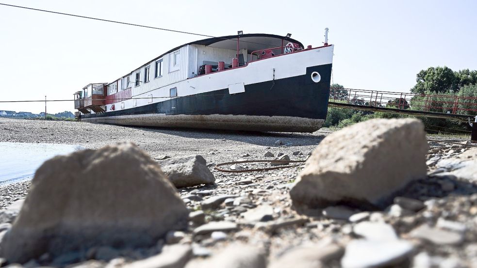 Trockengefallen liegt ein Schiff zwischen den Buhnen am Rhein bei Düsseldorf. Foto: Federico Gambarini/dpa