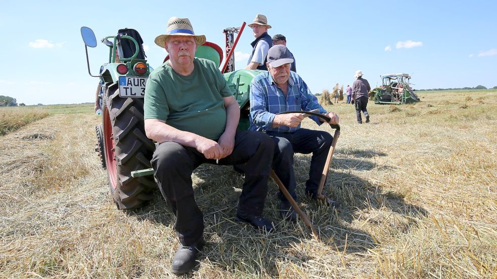 Friedrich Eilers (links) und Gerd Rinderhagen bei einer Erntepause. Rinderhagen schärft seine Sichte für die letzten Halme. Foto: Böning