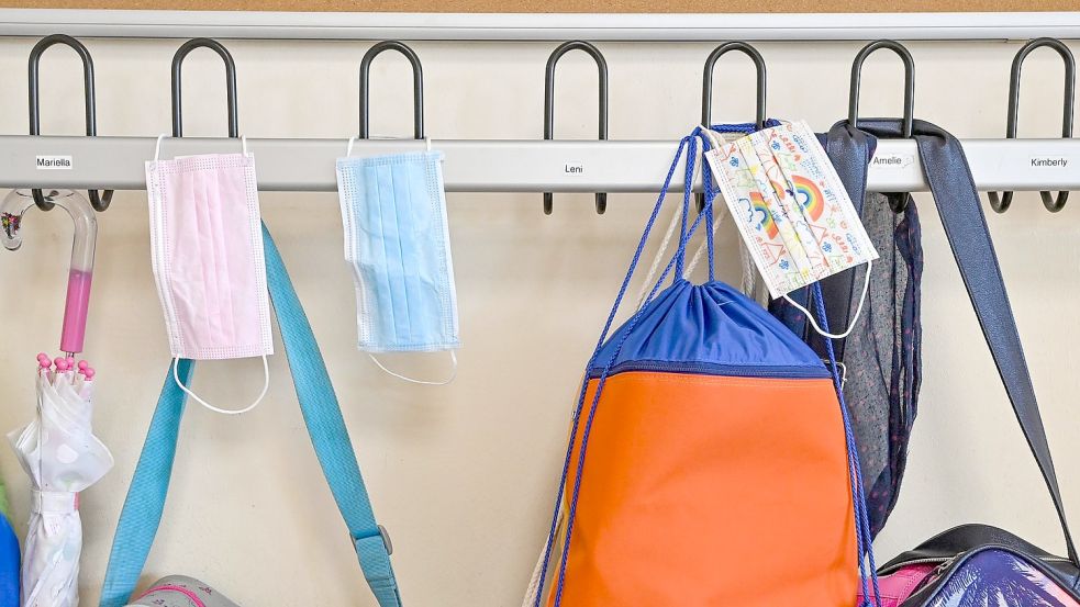 Masken hängen zusammen mit Taschen und Rucksäcken an Kleiderhaken in einem Klassenraum einer Grundschule. Foto: Patrick Pleul/dpa-Zentralbild/ZB
