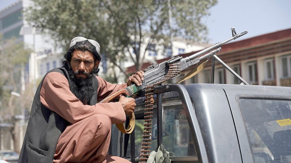 Ein Taliban-Kämpfer sitzt in Kabul mit einem Maschinengewehr auf der Ladefläche eines Fahrzeugs. Foto: -/AP/dpa