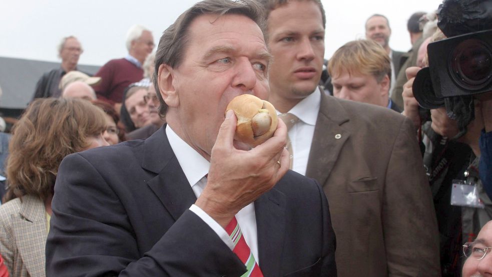 Viele deutsche Klischees in einem Bild: Der damalige Bundeskanzler Gerhard Schröder lässt sich 2005 bei einer Wahlkampfveranstaltung in einem Kleingartenverein eine Wurstsemmel schmecken. Foto: Imago Images/Sven Simon