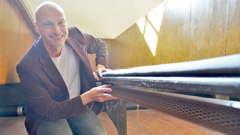 Pastor Frank Wessels ist begeistert von dem Modell der neuen Kirchenbankheizung, das bereits in Reihe 34 verbaut ist. Foto: Hoppe