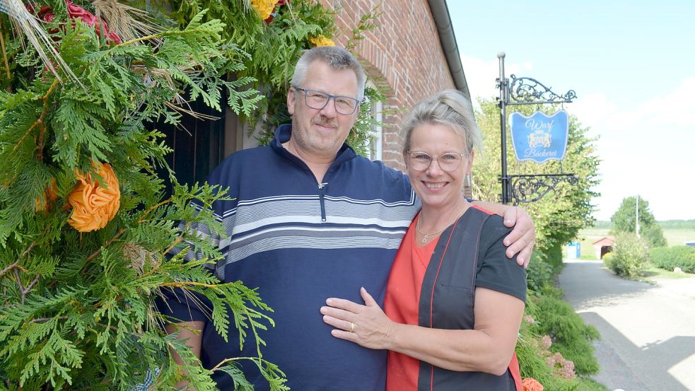 Karl-Heiz und Bettina Ubben stehen vor dem Eingang ihrer neuen Bäckerei im Eröffnungsbogen, den die Nachbarn vorbeigebracht haben. Foto: Hoppe